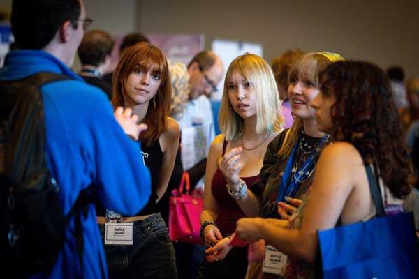 Five students in conversation in a crowd-filled room